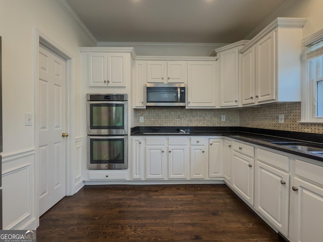 kitchen featuring stainless steel appliances, crown molding, dark wood finished floors, and white cabinetry