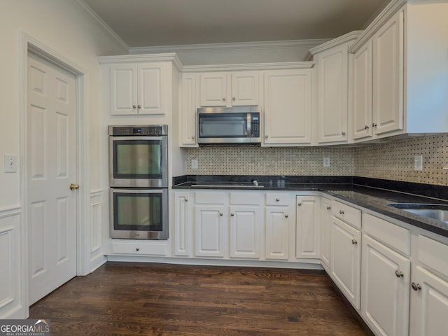 kitchen featuring stainless steel appliances, white cabinetry, tasteful backsplash, dark wood finished floors, and crown molding