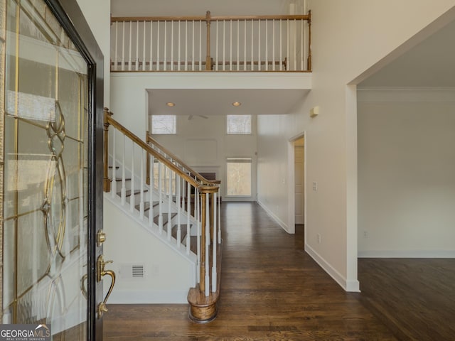 entrance foyer featuring a towering ceiling, baseboards, and wood finished floors