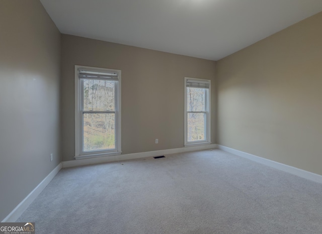 spare room featuring light carpet, baseboards, and visible vents