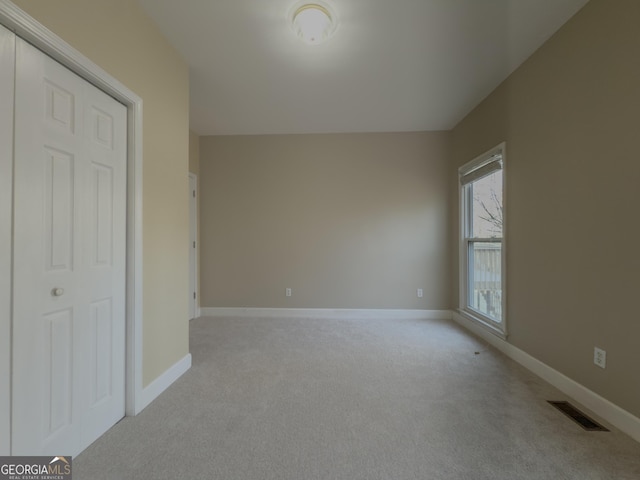 empty room featuring light carpet, baseboards, and visible vents