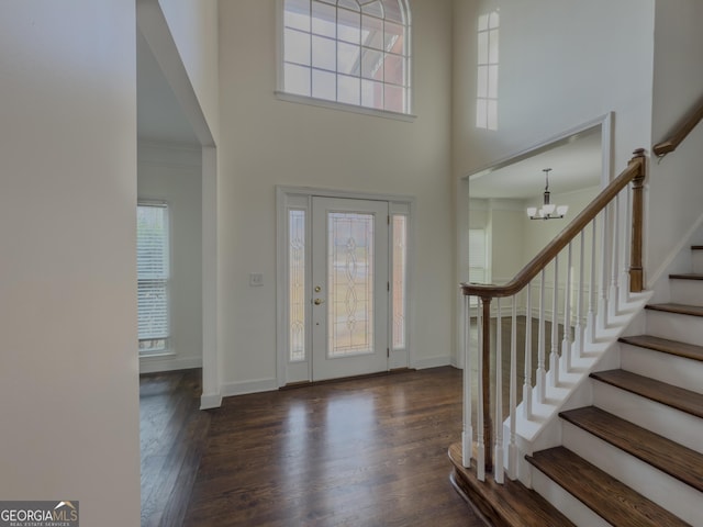 entryway with a high ceiling, ornamental molding, wood finished floors, baseboards, and stairs