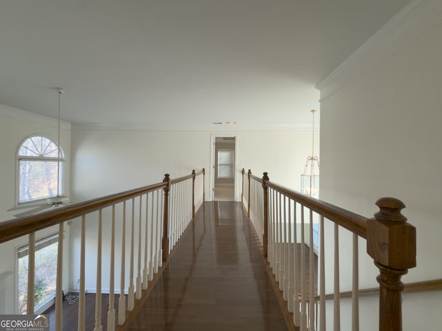 corridor featuring dark wood-style floors, ornamental molding, an upstairs landing, and a notable chandelier