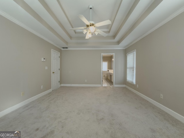 unfurnished bedroom with light carpet, baseboards, a raised ceiling, and ornamental molding