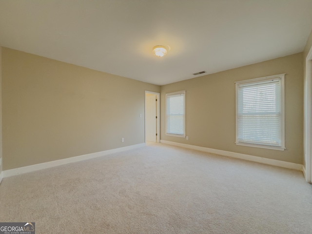 unfurnished room with light colored carpet, visible vents, plenty of natural light, and baseboards