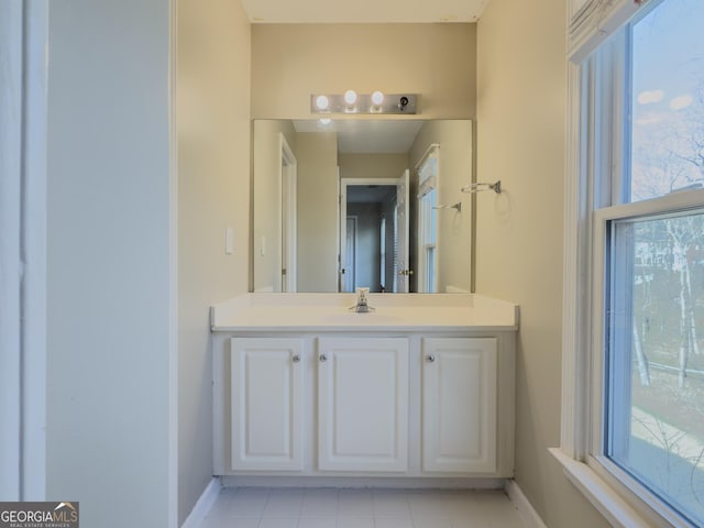 bathroom with baseboards, vanity, and a healthy amount of sunlight