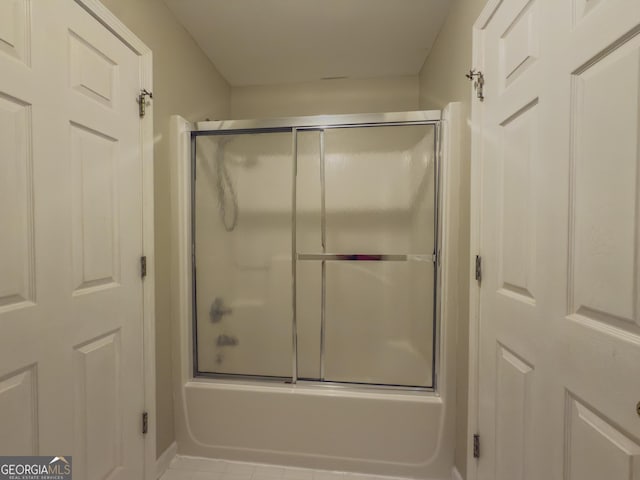 bathroom with combined bath / shower with glass door and tile patterned floors