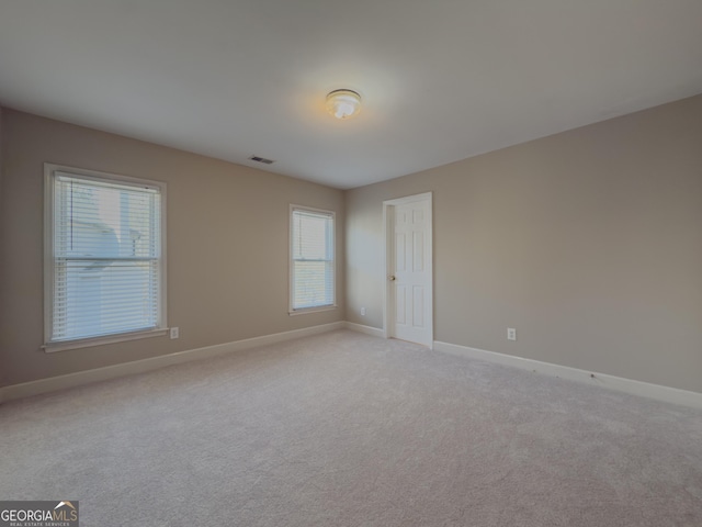 spare room with baseboards, visible vents, and light colored carpet