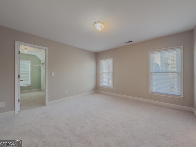 unfurnished bedroom with visible vents, light carpet, baseboards, and a spacious closet