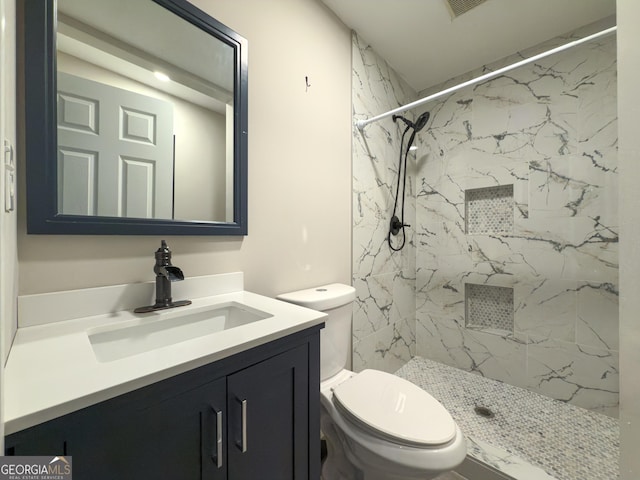 full bath with a marble finish shower, vanity, and toilet