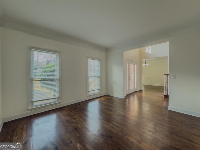 spare room featuring dark wood-style floors, ornamental molding, baseboards, and a notable chandelier