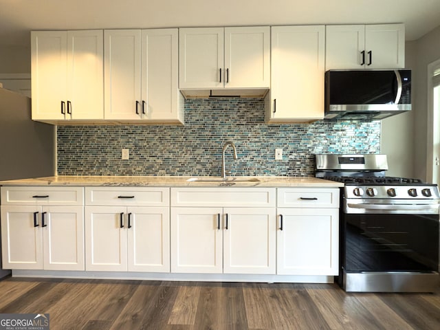 kitchen with backsplash, appliances with stainless steel finishes, white cabinets, and a sink