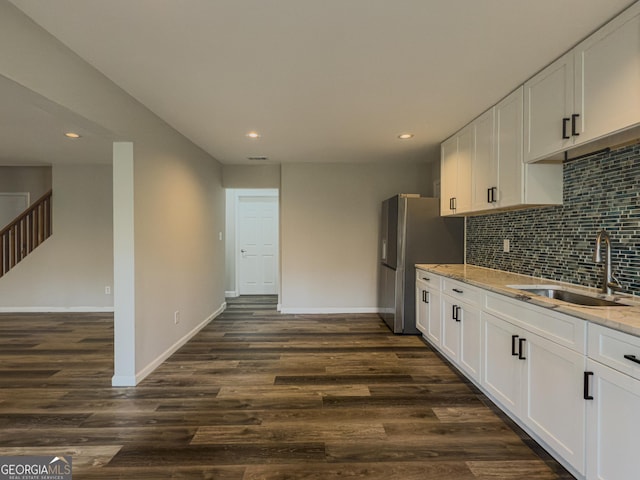 kitchen with baseboards, decorative backsplash, light stone counters, dark wood-style flooring, and a sink