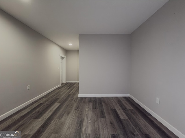 spare room featuring baseboards and dark wood-style flooring