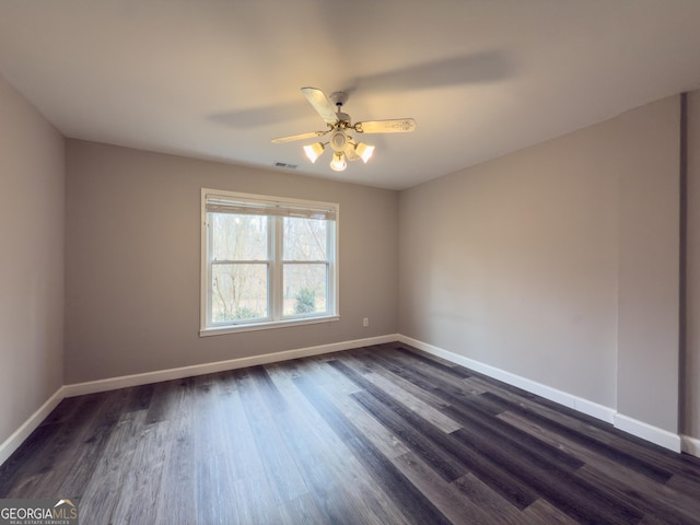 unfurnished room with ceiling fan, dark wood finished floors, visible vents, and baseboards