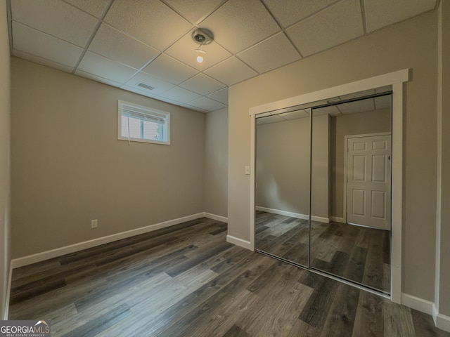 unfurnished bedroom featuring dark wood-style floors, a paneled ceiling, a closet, and visible vents