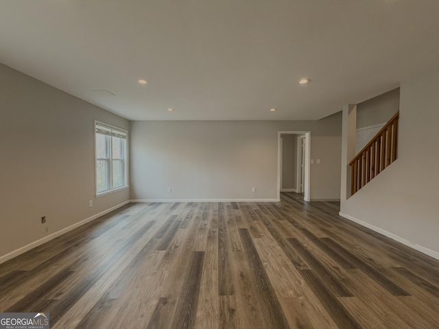 unfurnished living room featuring baseboards and dark wood finished floors