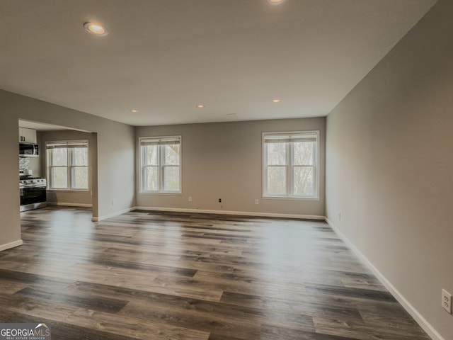 unfurnished living room featuring baseboards, dark wood finished floors, and recessed lighting