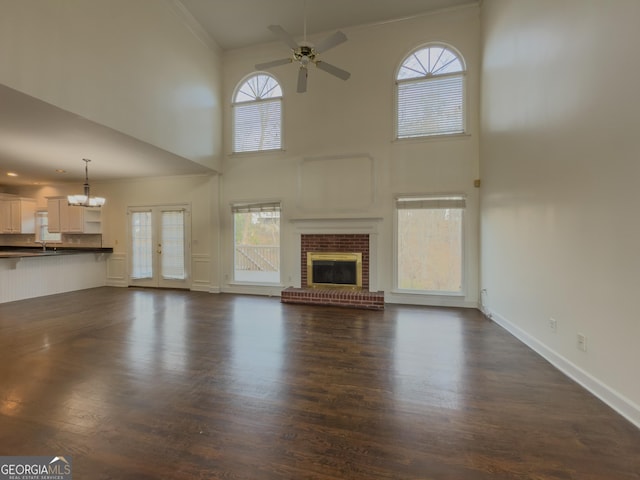 unfurnished living room featuring plenty of natural light, ornamental molding, ceiling fan with notable chandelier, and a fireplace