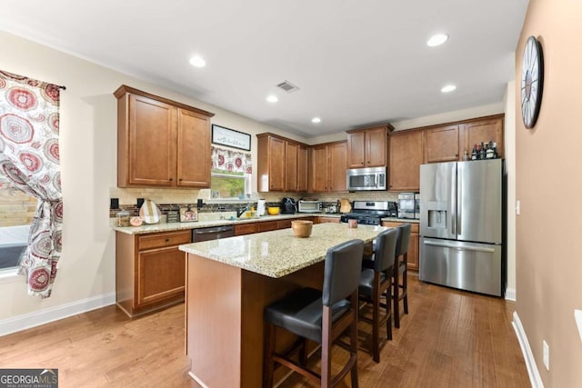 kitchen featuring visible vents, decorative backsplash, brown cabinets, dark wood-type flooring, and stainless steel appliances