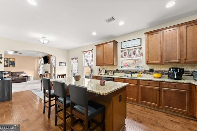 kitchen with visible vents, arched walkways, backsplash, and a kitchen breakfast bar