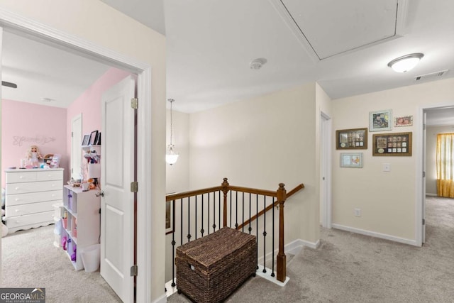 hall featuring carpet floors, visible vents, attic access, an upstairs landing, and baseboards