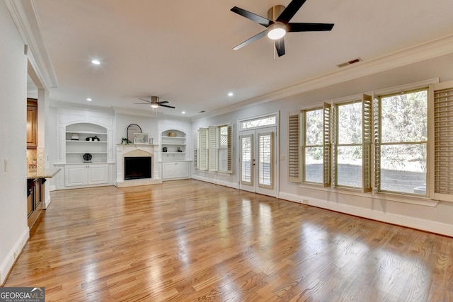 unfurnished living room with a fireplace with raised hearth, ornamental molding, light wood-style flooring, and visible vents