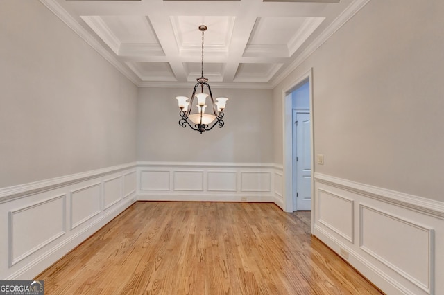 unfurnished dining area with light wood-style flooring, beam ceiling, coffered ceiling, and a notable chandelier