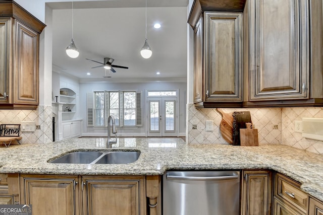 kitchen featuring dishwasher, pendant lighting, a sink, and light stone countertops