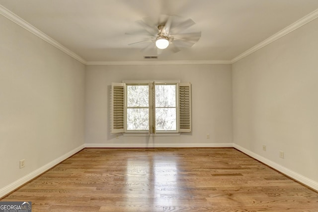 empty room featuring ceiling fan, visible vents, ornamental molding, and wood finished floors