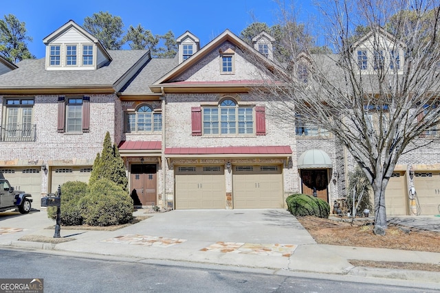 view of property with an attached garage, a shingled roof, concrete driveway, and brick siding