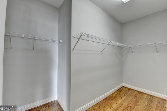 walk in closet with wood finished floors