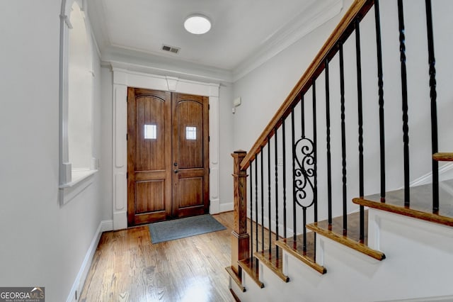 entrance foyer featuring ornamental molding, wood finished floors, visible vents, and baseboards