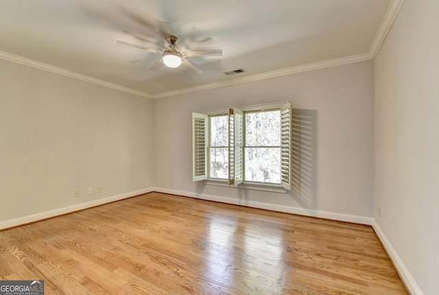 empty room with baseboards, visible vents, ceiling fan, wood finished floors, and crown molding