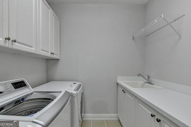 washroom featuring cabinet space, light tile patterned floors, baseboards, separate washer and dryer, and a sink