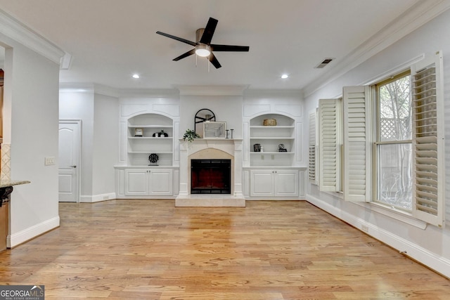 unfurnished living room with baseboards, a fireplace with raised hearth, built in features, ornamental molding, and light wood-type flooring