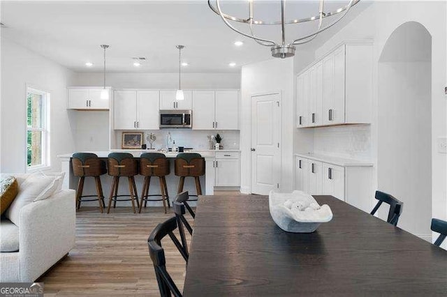 dining room featuring light wood-type flooring, an inviting chandelier, arched walkways, and recessed lighting