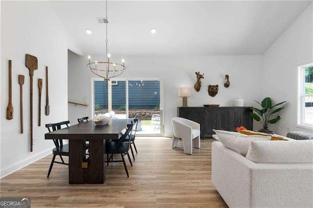 dining space featuring light wood finished floors, a wealth of natural light, and a notable chandelier