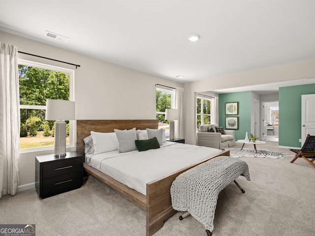 bedroom with light carpet, visible vents, and baseboards