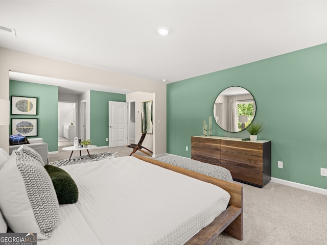 carpeted bedroom with ensuite bath, baseboards, and visible vents