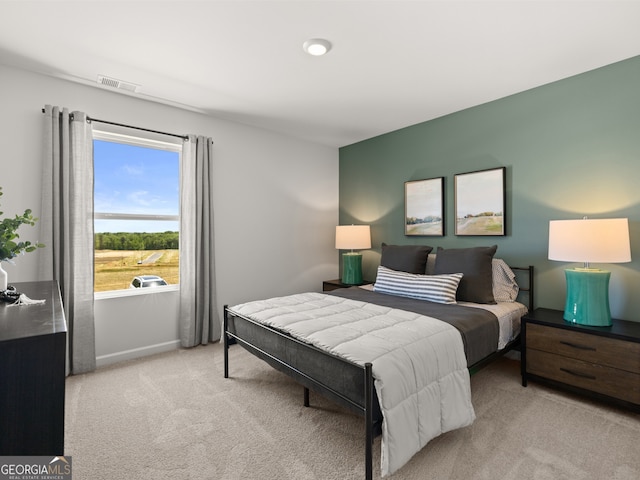 bedroom with baseboards, visible vents, and light colored carpet