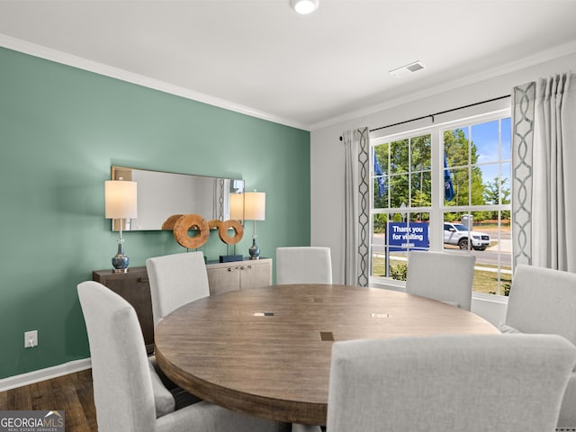 dining area featuring visible vents, baseboards, crown molding, and wood finished floors