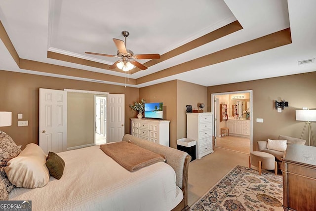 bedroom with ensuite bath, visible vents, a raised ceiling, and light colored carpet