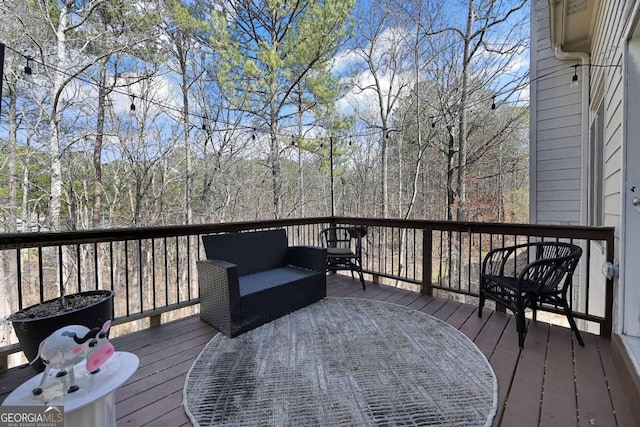 wooden terrace with outdoor lounge area and a wooded view