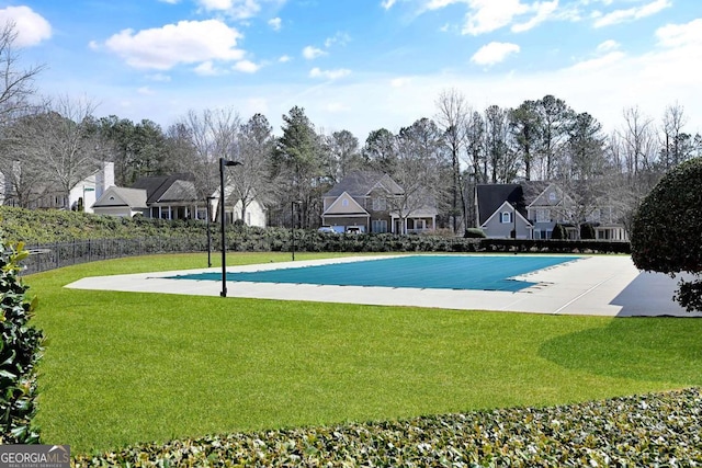 view of pool with a residential view, fence, and a lawn