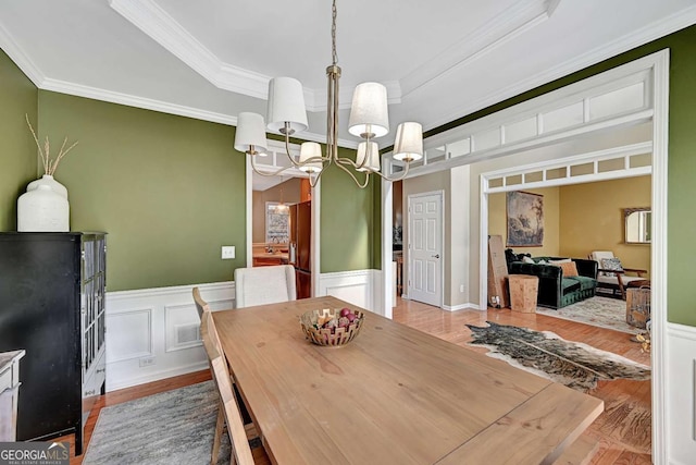 dining space featuring wood finished floors, a raised ceiling, and a notable chandelier