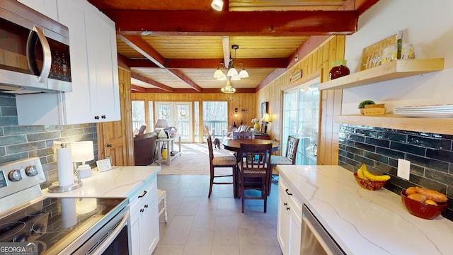 kitchen featuring appliances with stainless steel finishes, beamed ceiling, decorative backsplash, and white cabinets