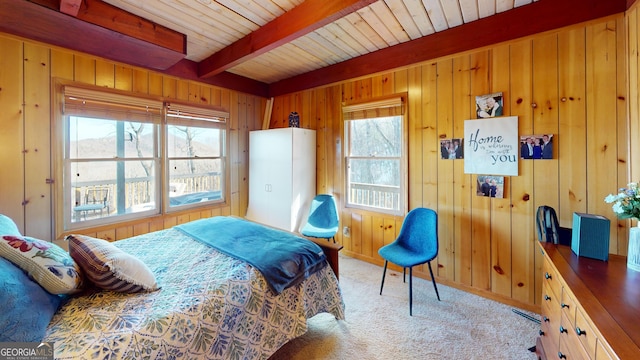 bedroom with beamed ceiling, carpet, wood ceiling, and wooden walls