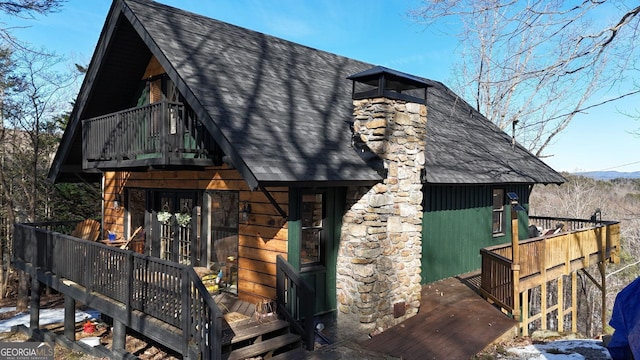 exterior space featuring a deck with mountain view, a shingled roof, and a balcony