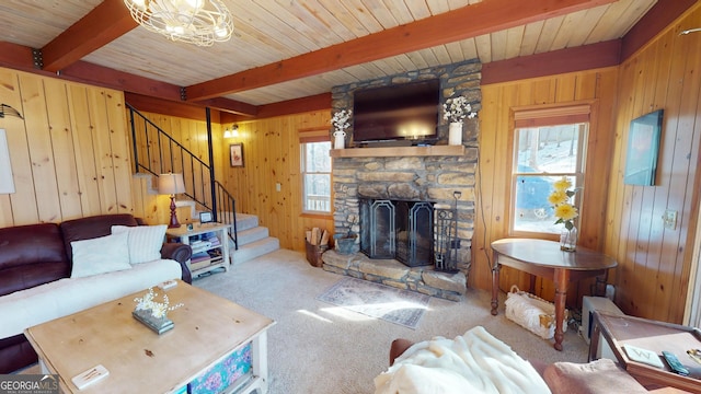 carpeted living area featuring a fireplace, wood walls, beamed ceiling, and stairs